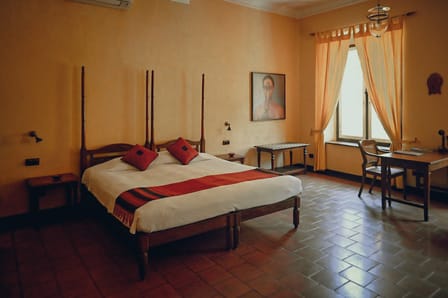 Superior Double Room at Old Harbour Hotel: four-poster bed on terracotta tiles with a desk by the curtained window