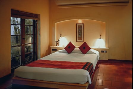 Cottage Room at Old Harbour Hotel: double bed with red cushions beside glazed doors opening to the garden