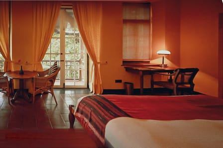 Double Room with Garden View at Old Harbour Hotel: bed, cane chairs and a writing desk by tall curtained windows