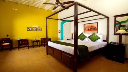 Tea Bungalow, Fort Kochi: Heritage Premium Room with a dark wood four-poster bed, yellow walls and white beamed ceiling