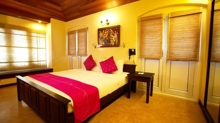 Tea Bungalow, Fort Kochi: Heritage Deluxe Room with wooden bed, pink throw and cushions, bamboo blinds and timber ceiling