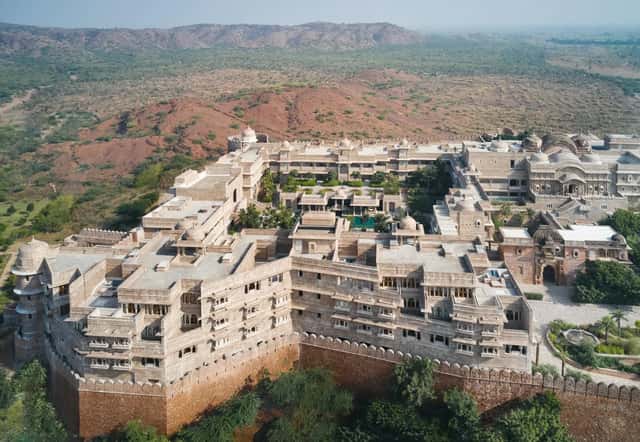 Aerial view of the whole walled fort: ramparts, domes, courtyards and pool, with the Aravali landscape behind. No people.
