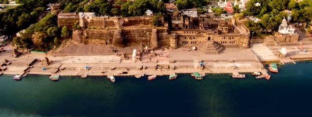 Ahilya Fort rising above the ghats and boats of the Narmada at Maheshwar, seen from the air