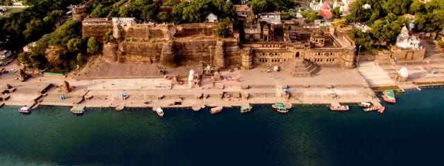 Ahilya Fort rising above the ghats of the Narmada at Maheshwar, boats on the river below