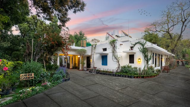 The white 1937 bungalow at dusk, with its garden, herb beds and blue shutters, Lutyens Bungalow, New Delhi