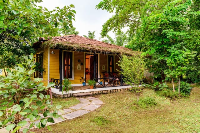 A yellow timber cottage with a tiled roof and its own verandah