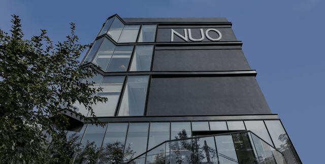 Black glass-and-steel exterior of NUO with the hotel logotype against a blue sky