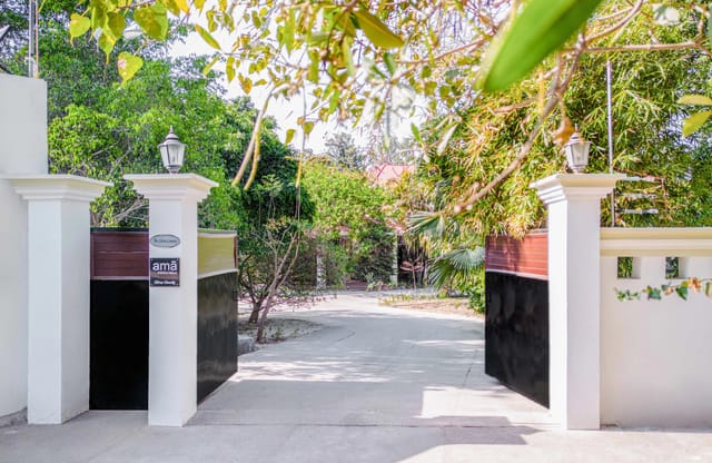 Gated entrance of Citrus County with amã Stays & Trails signage, driveway curving into the orchard
