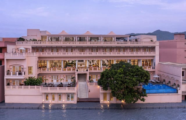 Pink tiered facade of the hotel rising above the Ganges at dusk at Pilibhit House, Haridwar