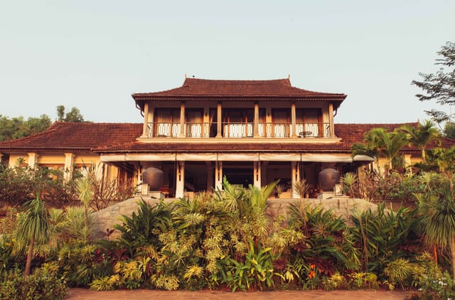 Main villa with tiled roofs, pillared upper balcony and tropical garden planting at Kahani Paradise, Gokarna