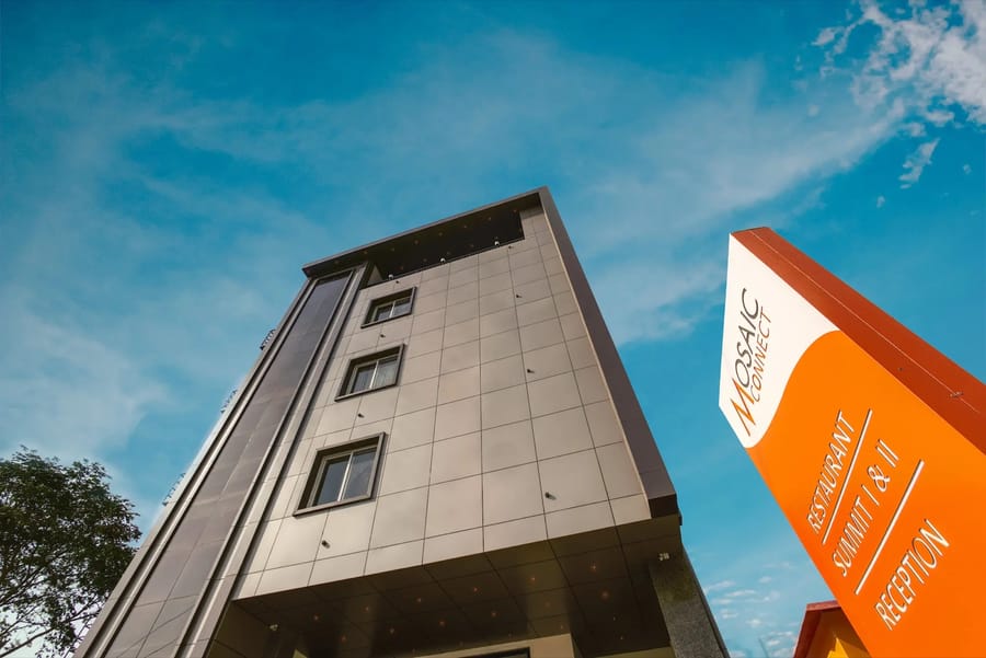 Street-level view of the dark-tiled facade and orange Mosaic Connect sign, Mosaic Connect Ayodhya, Ayodhya