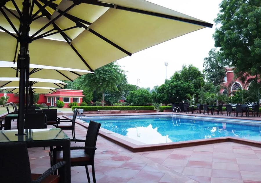 Shaded tables by the pool at the Maharaja Ganga Mahal