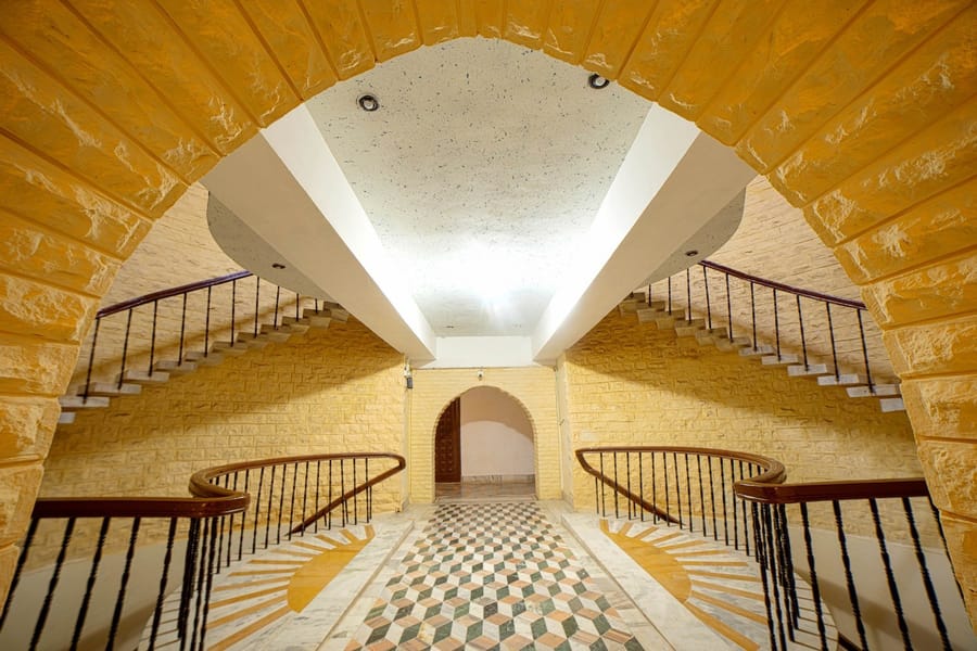 Golden sandstone atrium with twin curved staircases