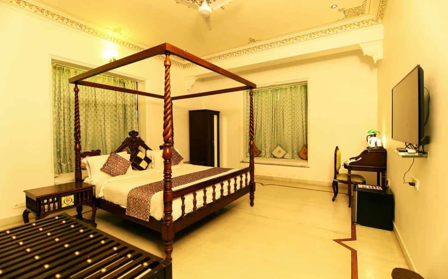 Four-poster bed in a haveli room with window drapes