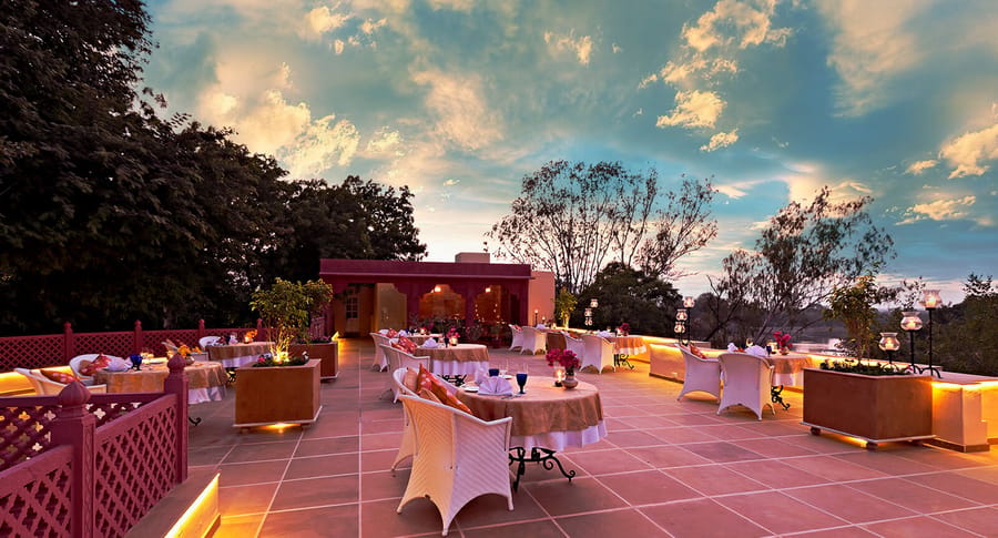 Terrace dining under a sunset sky with white-clothed tables and lanterns