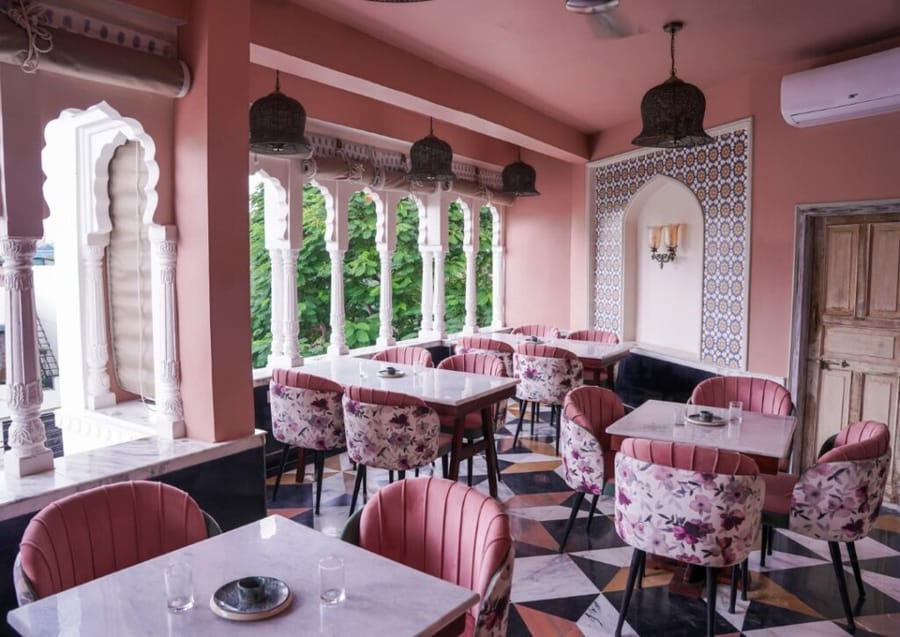 Pink arches and floral chairs in the rooftop restaurant at Dev Mahal, Jaipur