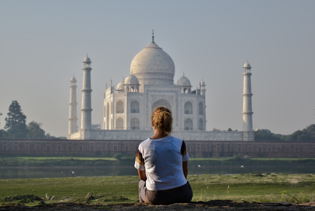 Traveller sitting alone looking at the Taj Mahal from across the Yamuna river