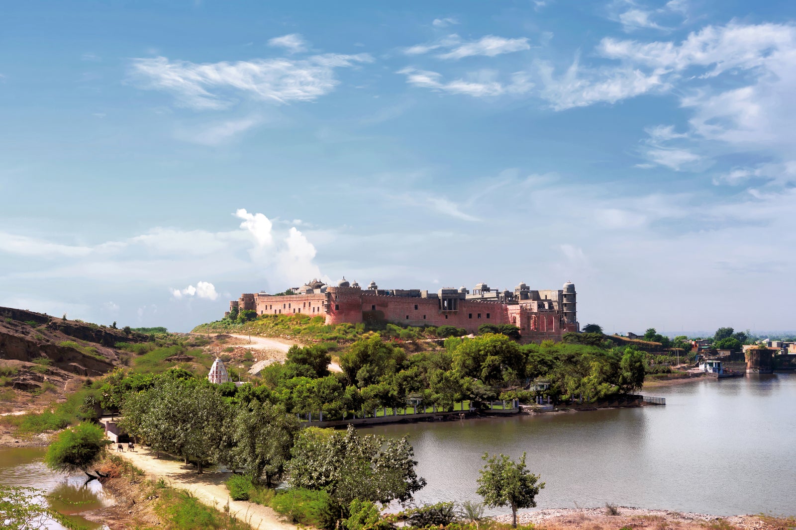 The fort on its hill seen from across Barwara lake, small white temple in the foreground trees. From the opening press release.